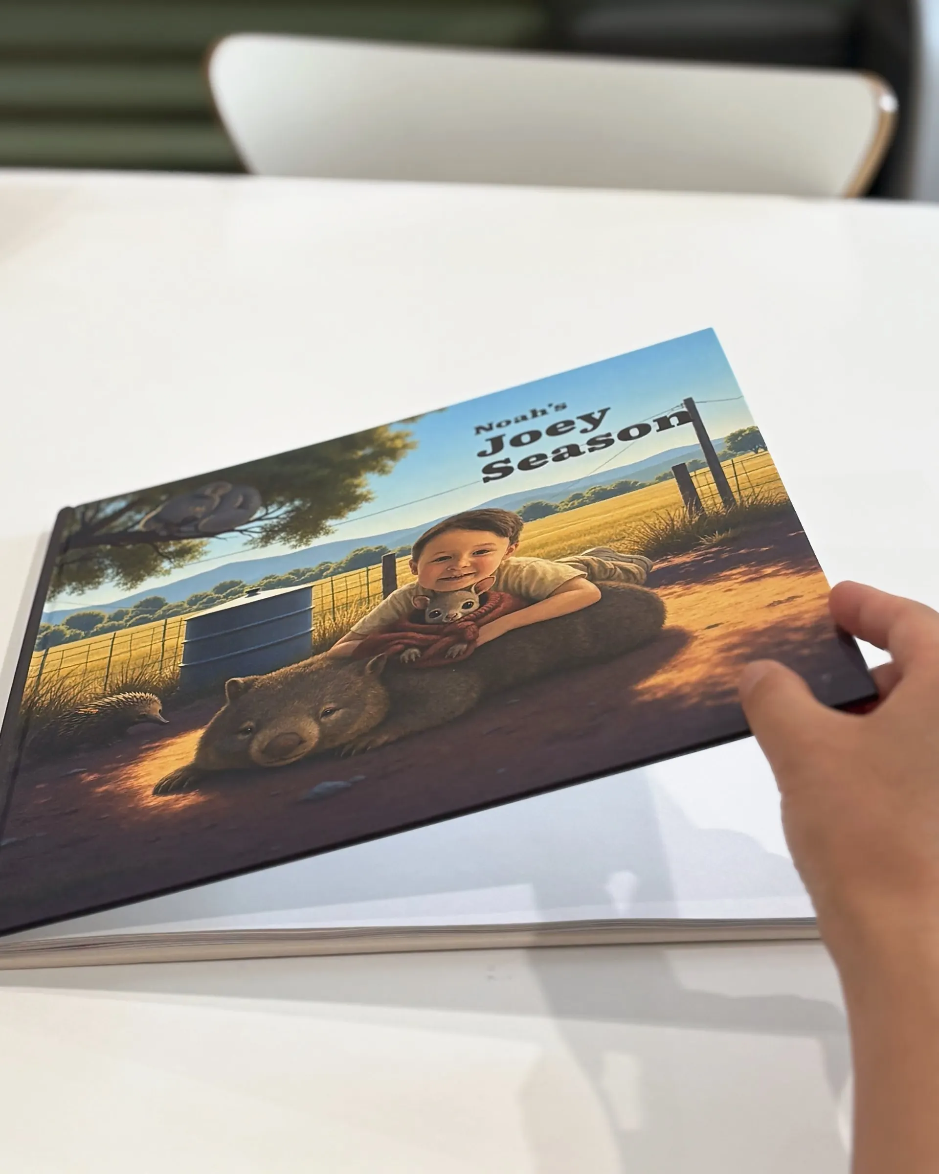 A hand lifting the cover of a printed Joey Season book.