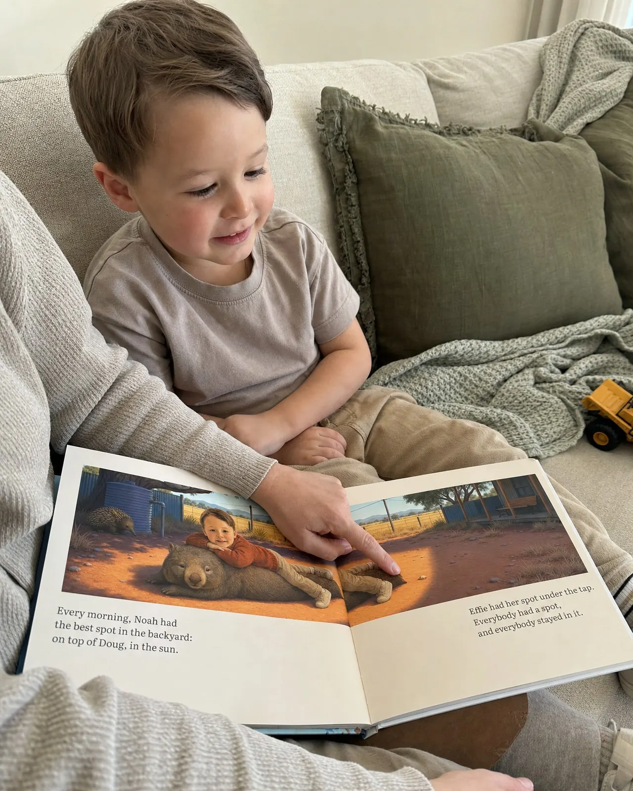 A child and a grown-up reading a picture book together.